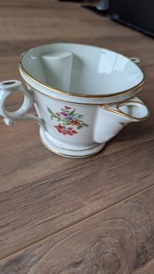 une tasse blanche à bord doré posée sur une table en bois