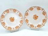 two plates with orange flowers on them on a white surface