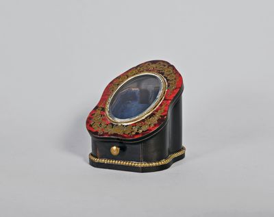 une petite boîte noire et dorée contenant une pierre bleue