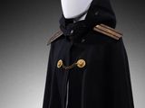a white mannequin wearing a black cape with gold buttons