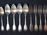 six spoons and six forks are lined up on a black surface
