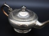 a silver tea pot on a black table