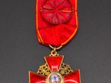 a close up of a red and gold medal with a cross on it