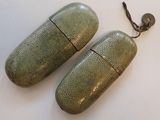 pair of green metal pill cases sitting on top of a white surface