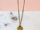 un collier en or orné d'une pièce, posé sur une surface en marbre