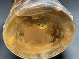 someone is holding a glass with a liquid inside of it on a table