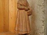 a wooden statue of a woman holding a basket on a shelf