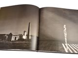 an open book with a black and white photo of a person standing in a field