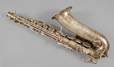 an old silver saxophone sitting on top of a gray surface