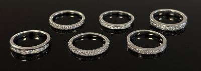 six silver rings with diamonds on a black surface