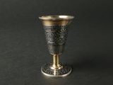 une coupe en argent bordée d'or, posée sur une surface noire