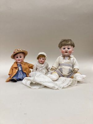 trois poupées en porcelaine représentant des enfants assis sur une couverture