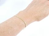 a woman ' s hand with a gold bracelet on it