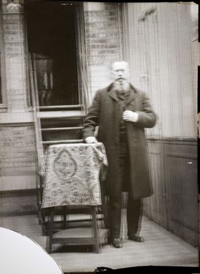 a black and white photo of a man standing on the porch of a house