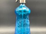 une image représentant une bouteille en verre bleue munie d'une poignée métallique
