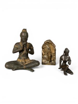trois figurines en bronze représentant un homme et une femme assis sur un rocher