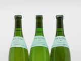 trois bouteilles de vin posées les unes à côté des autres sur une surface blanche