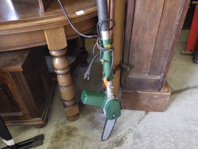 un aspirateur vert et argent posé par terre à côté d'une table en bois