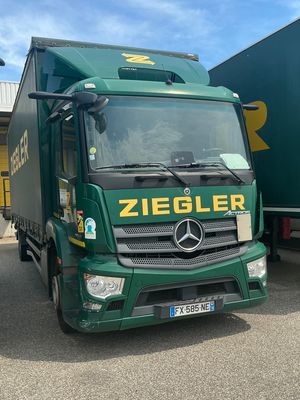 two green trucks are parked next to each other in a parking lot