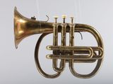 a brass trumpet hanging from a string on a gray background