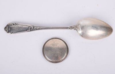 Une vieille cuillère et une pièce de monnaie sont posées sur une surface blanche