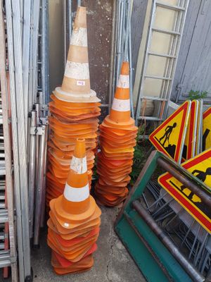 several orange traffic cones are stacked on top of each other in front of a fence