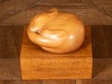 a wooden sculpture of a cat sleeping on top of a wooden box