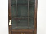 une vieille armoire en bois avec une porte vitrée et une clochette sur le dessus
