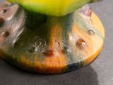 a green vase with a yellow flower on top of it