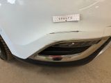 the front end of a white car with a sticker on it ' s bumper