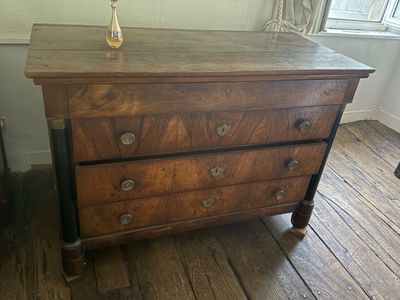 a wooden chest of drawers with a vase on top of it