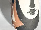 a vase with a face painted on it sitting on a table
