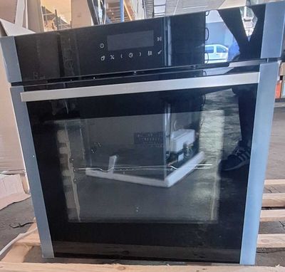 un four noir posé sur une palette dans un entrepôt
