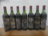 six bouteilles de vin posées sur une table devant un mur blanc