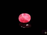 a close up of a pink stone on a black surface