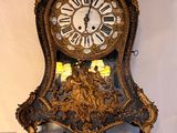 une horloge accrochée au mur à côté d'un tableau représentant un oiseau