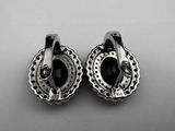 a pair of silver earrings with black stones on them