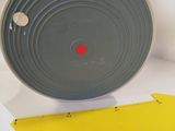 a yellow ruler next to a gray object on a white surface