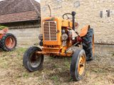 deux vieux tracteurs garés devant un bâtiment en briques