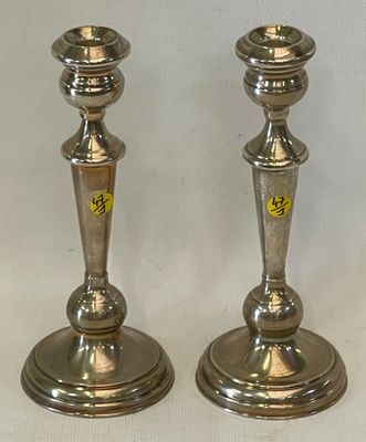 two silver candlesticks sitting on a white table