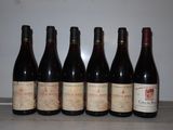 six bouteilles de vin rouge sont alignées sur un comptoir