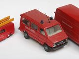 quatre camions miniatures alignés sur une surface blanche