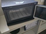 a microwave sitting on a counter with a monitor on it