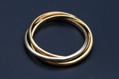 un gros plan d'une bague en or et en argent sur une surface noire