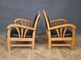 two wooden chairs with black leather seats sitting on a parquet floor