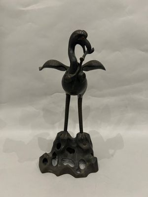 an old bronze statue of a bird on a rock on a white background