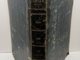un vieux livre à la couverture noire posé sur une table blanche