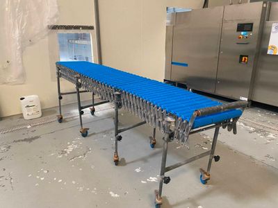 un tapis roulant bleu dans une usine, avec une machine en arrière-plan