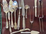 a lot of silverware on a table with a knife, spoon, fork and spoon rest