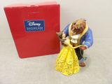 La figurine de « La Belle et la Bête » se trouve à côté d'une boîte rouge.